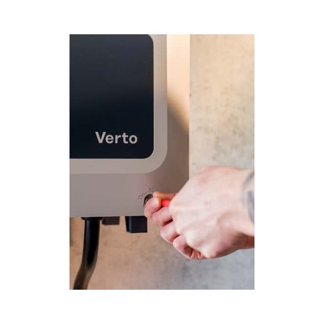 Détail du raccordement d’un onduleur Fronius Verto : une main insère un connecteur sous le capot latéral marqué Verto.