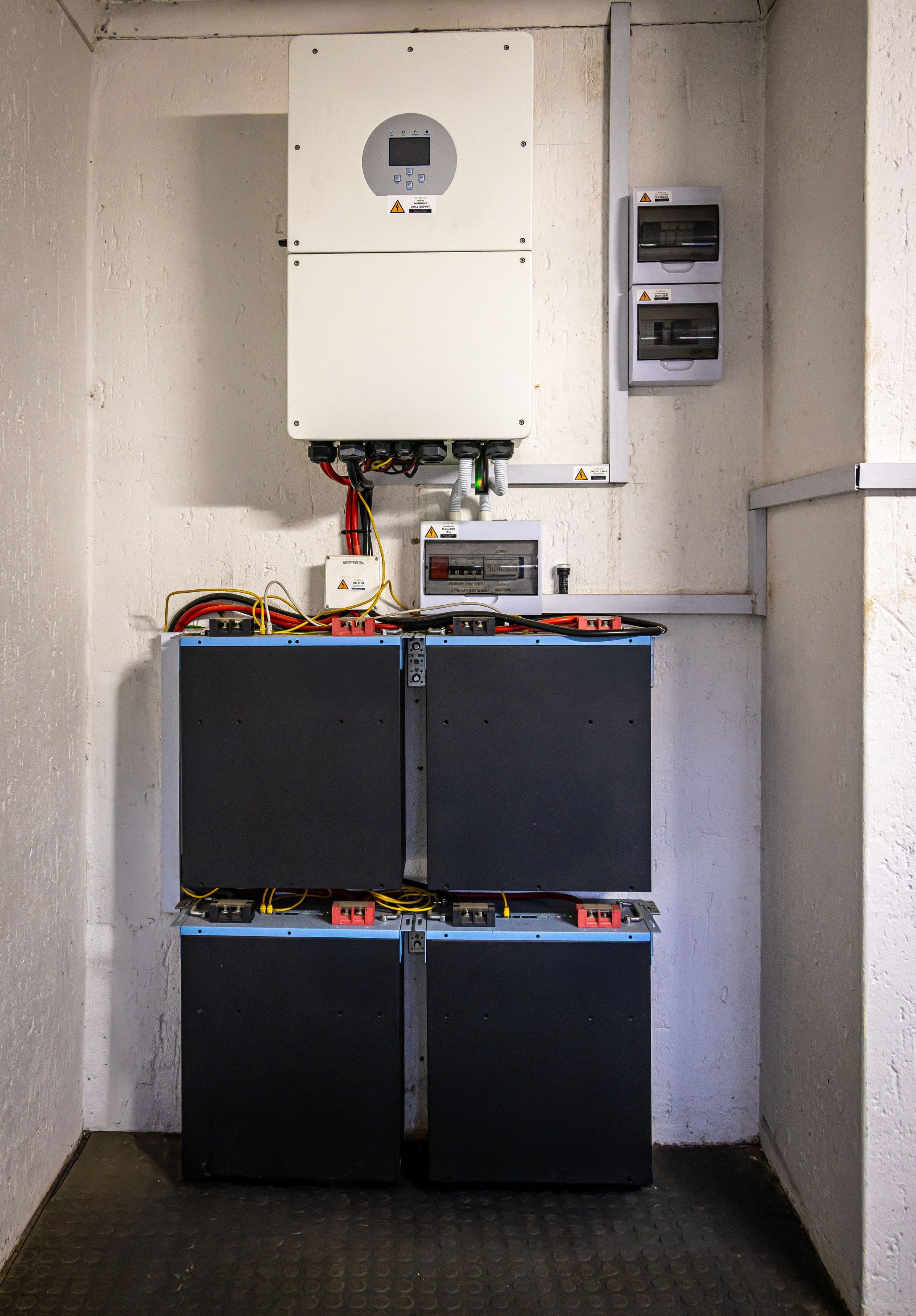 Local technique avec onduleur et rack de batteries de stockage lithium montés au mur.