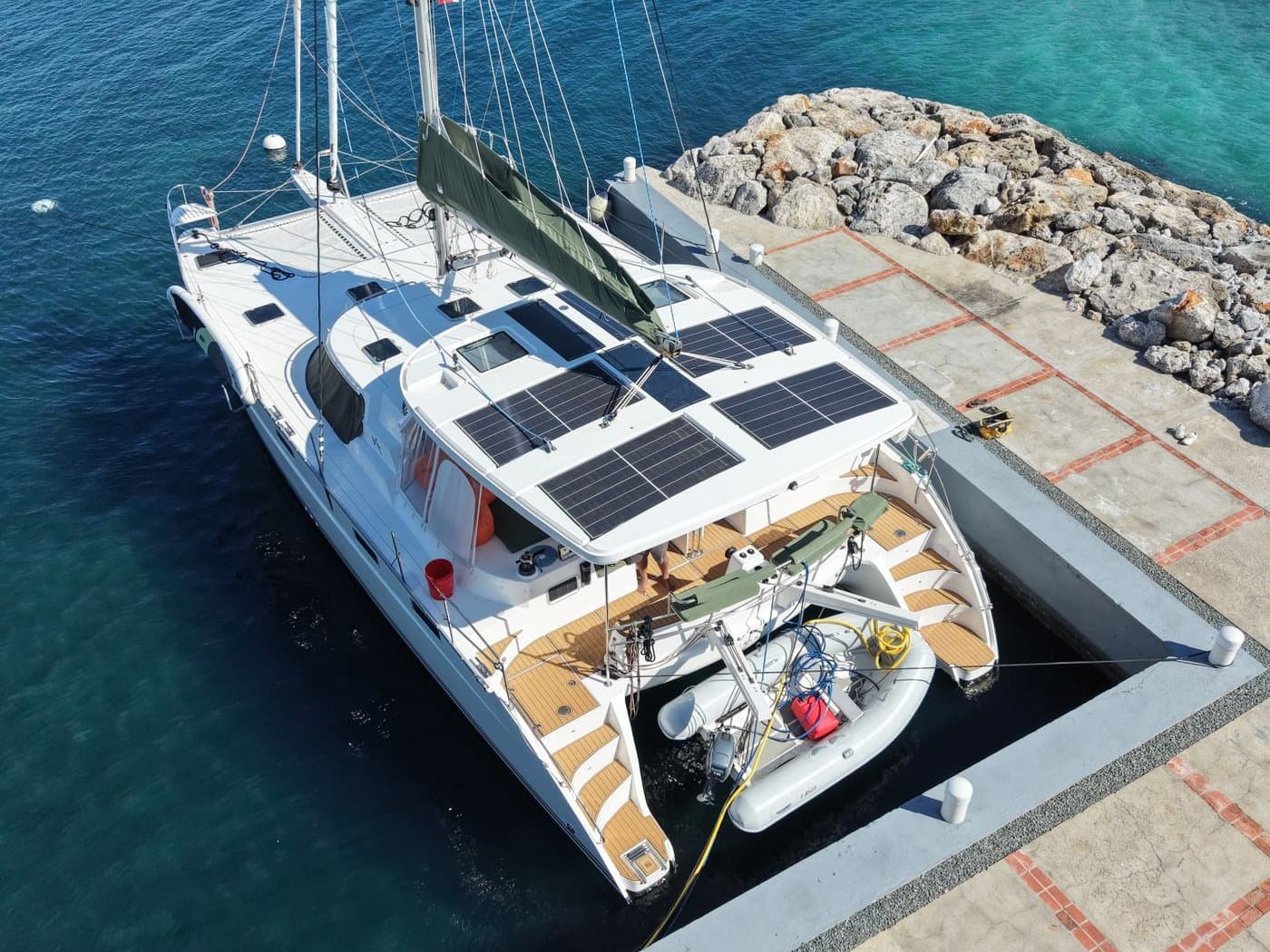 Catamaran à voile amarré le long d’un quai, six panneaux solaires alignés sur le toit du roof.
