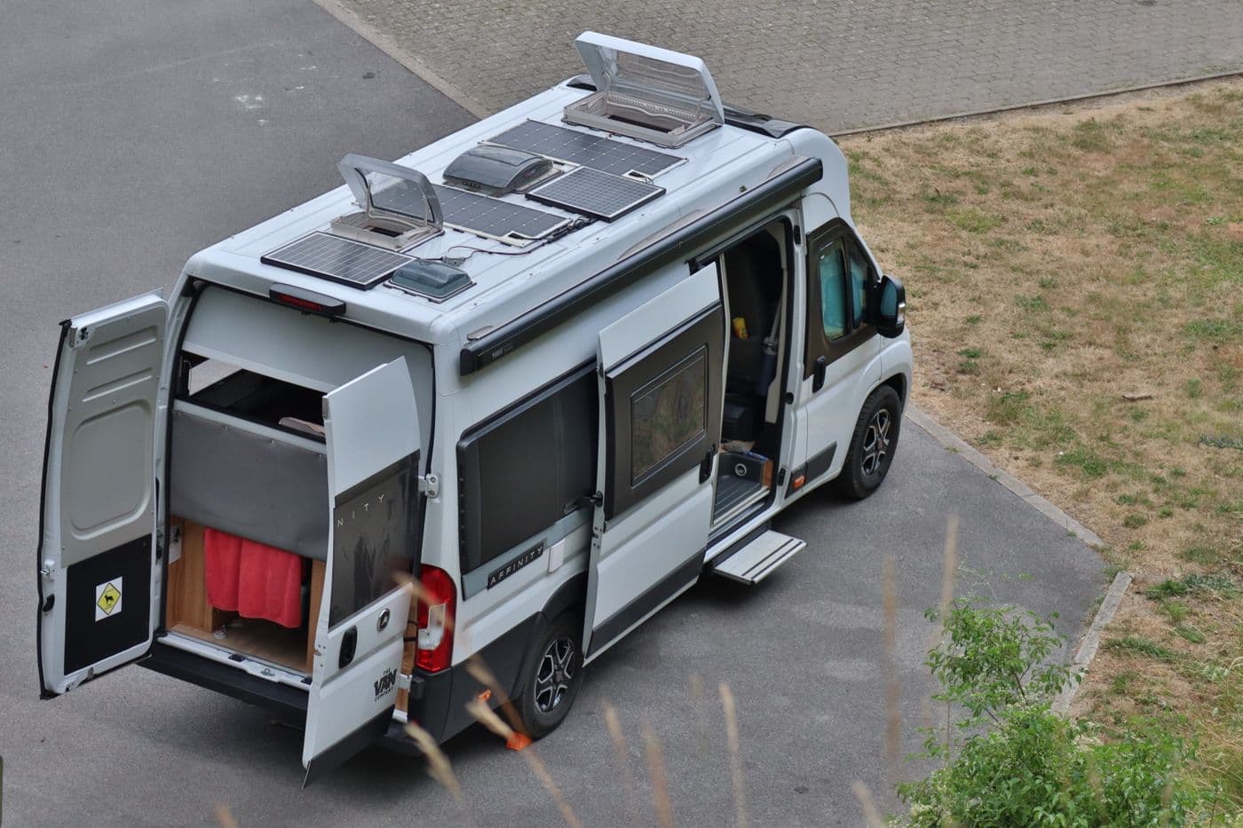 Fourgon aménagé vu de dessus, trois panneaux solaires posés sur le toit entre les lanterneaux ouverts.